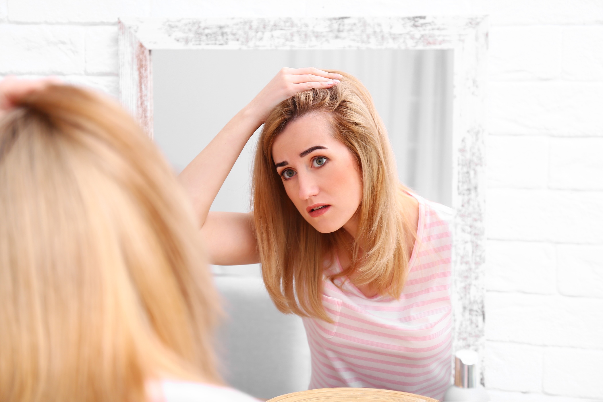 Woman inspecting scalp for hair loss after minoxidil use